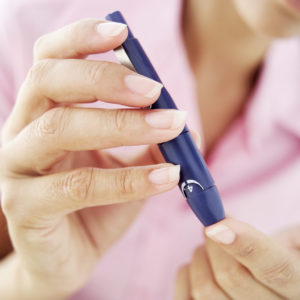 Woman Removing Blood from Her Finger for a Blood Test --- Image by © Royalty-Free/Corbis